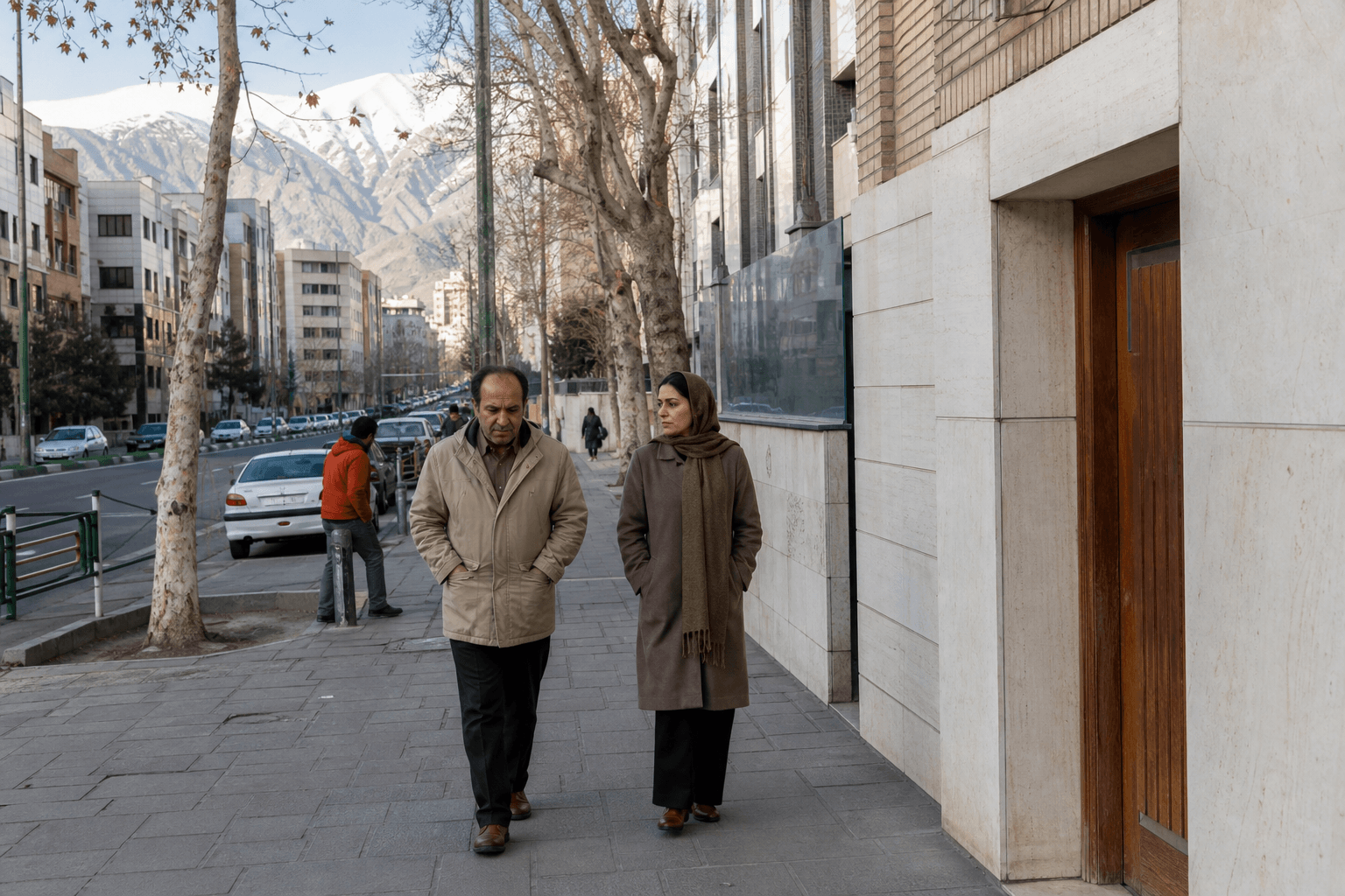 زن و مرد در پیاده‌رو شمال تهران راه می‌روند، درخت چنار و کوه در پس‌زمینه